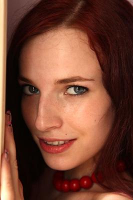 18P Young redhead Leila Smith drapes herself in a feather boa while modeling naked