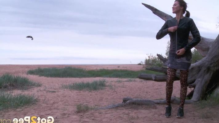 15P Solo girl takes a pee on a beach while wearing sexy hosiery and a leather coat