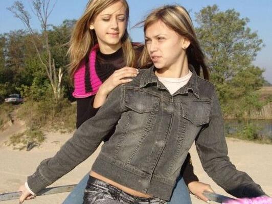 10P Young girls in denim jeans and jackets hold hands while non nude at the beach