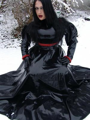 16P Goth woman Lady Angelina models a black latex dress on snow-covered ground