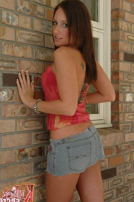 12P Redhead amateur Kylie places hands over her naked tits against a brick wall