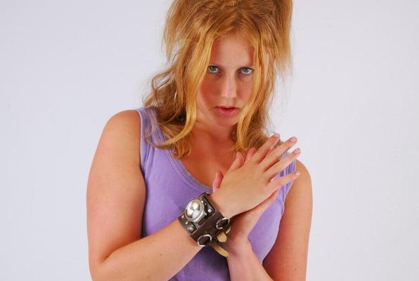 16P Natural redhead models a large cuff watch in a tank top and faded jeans