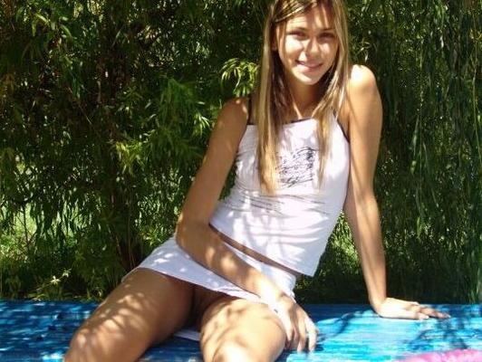 15P Teen amateur crosses and uncrosses her legs on an outdoor bench in a miniskirt