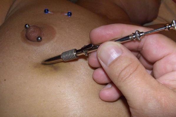 12P Close up action of a female having her breasts tortured with needles