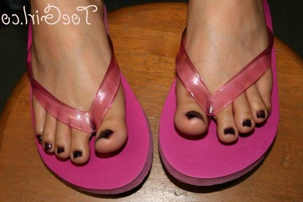 16P Caucasian female displays her painted toenails in a pair of flip flops