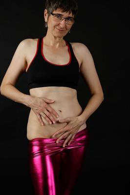20P Mature woman models a sports bra in shiny pants and black boots