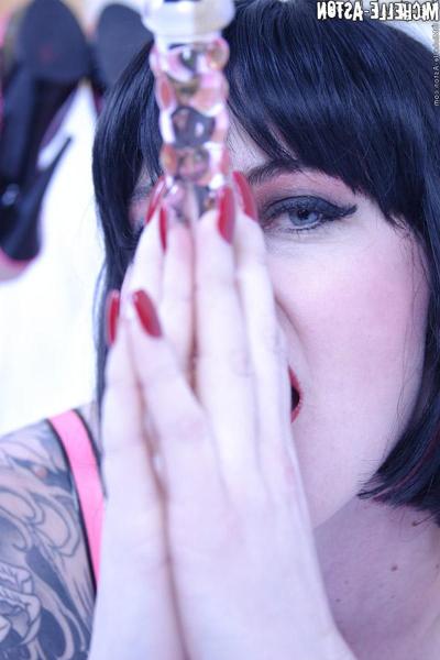 15P Tattooed brunette Michelle Aston plays with a crop as well as a glass dildo