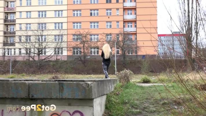 15P Blonde girl Jenna Lovely pisses over a concrete platform in view of a building