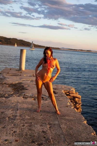 16P Brunette MILF Roxeanne models totally naked on a concrete pier