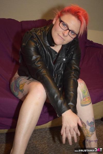 20P Inked redhead removes leather clothing to model in sexy lingerie