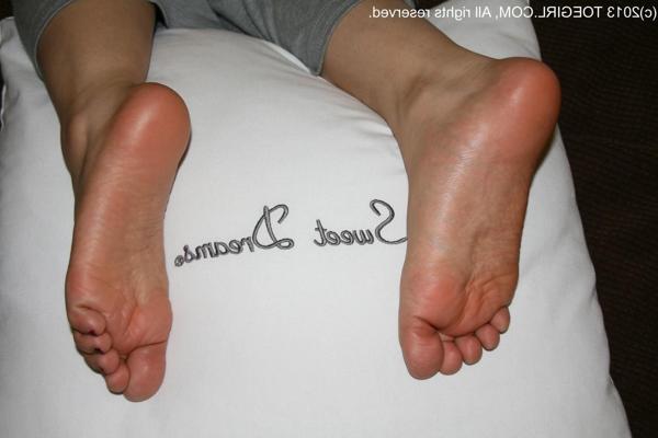 16P Caucasian female displays her bare feet over a pillow in sweat pants