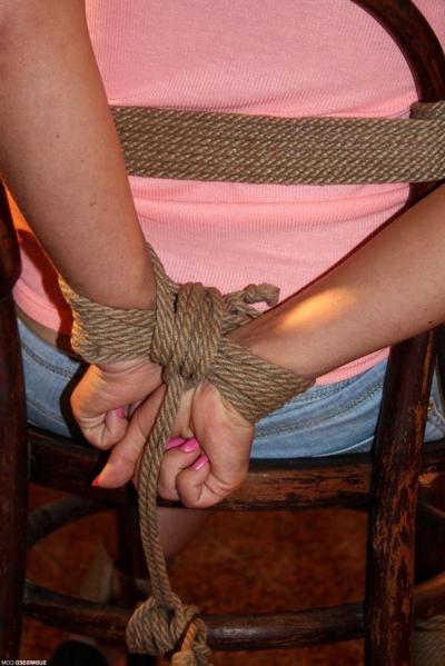 12P Blonde female in denim shorts is gagged and tied to a chair in an empty room