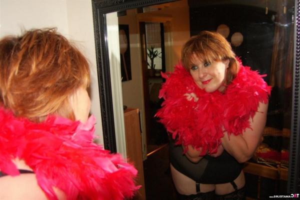 16P Older redhead shows her tits and twat while draped in a feather boa
