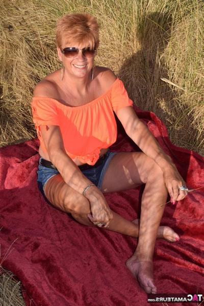 20P Mature redhead Dimonty shows her tits on a bench in a country field