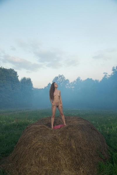 20P Glamorous babe Arina G strips in a bale of hay and poses naked in the mist