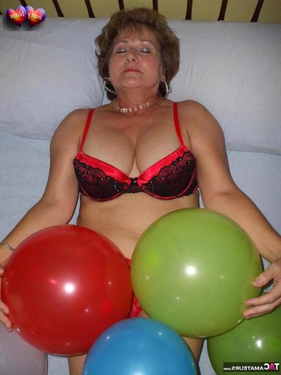 20P Mature woman Busty Bliss goes topless on her bed while playing with balloons