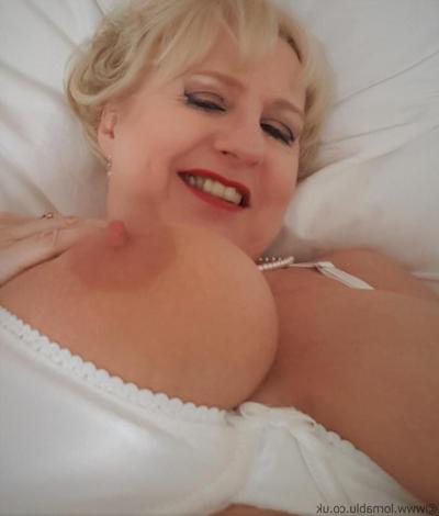 15P British woman Lorna Blu shows off her big tits in white lingerie on her bed