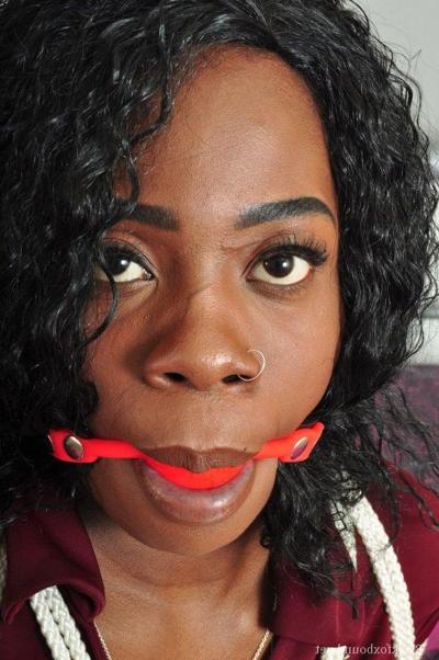 16P Ebony female is tied up on a bed while gagged and fully clothed